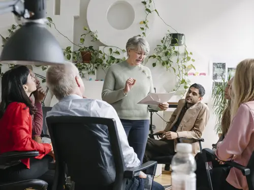 Mennesker i ring som hører på en eldre dame snakke