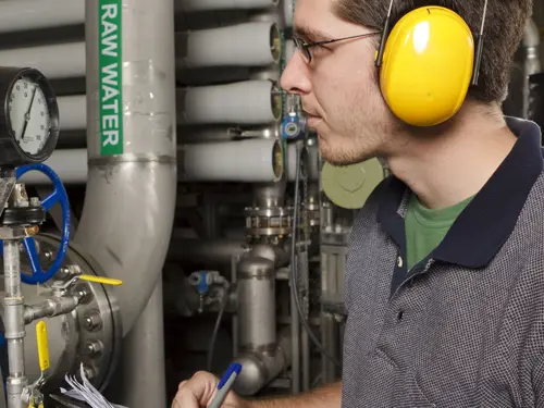 Foto av mann med hørselsvern som justerer ventiler på vannverk