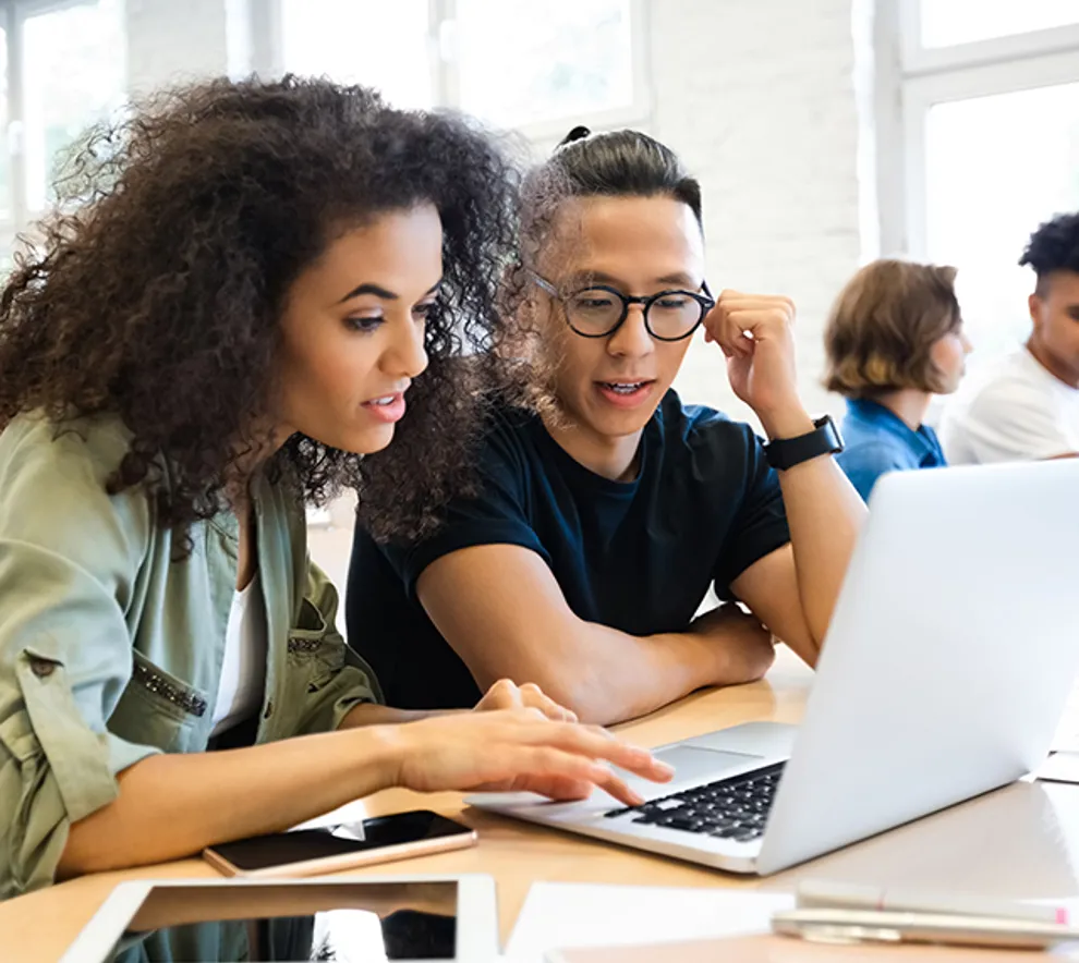 En gutt og en jente som sitter sammen og ser på en pc