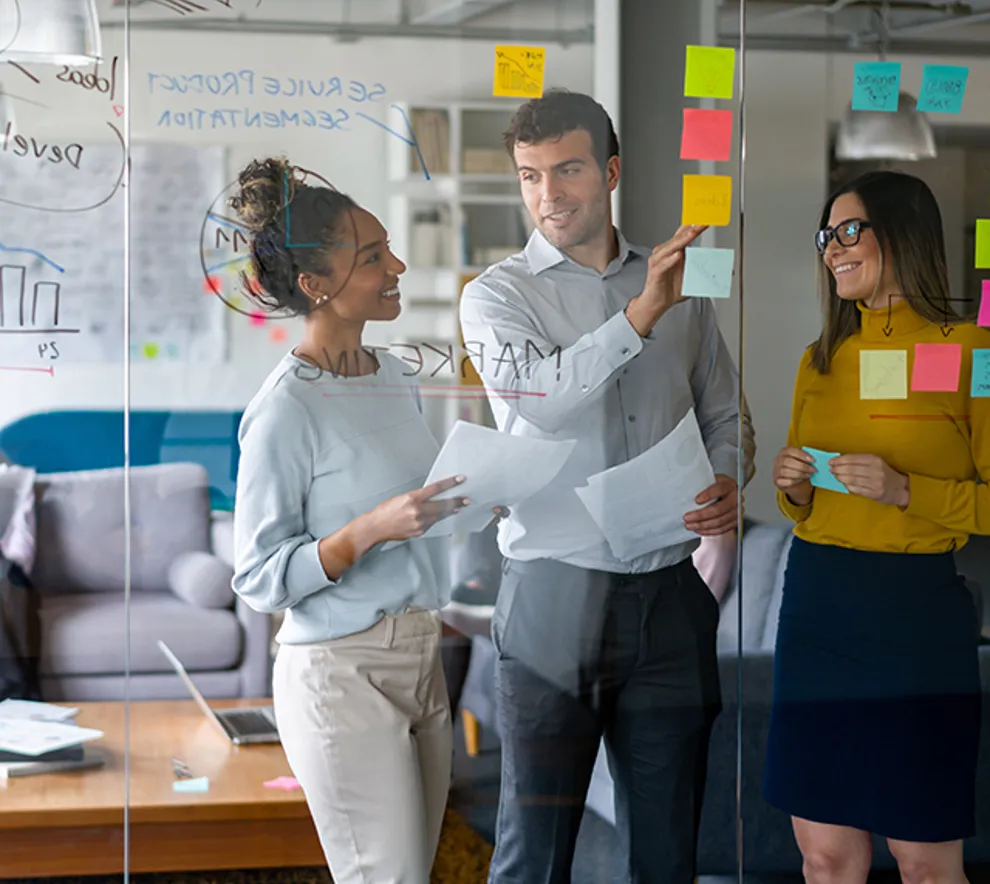 Tre mennesker som står sammen og brainstormer