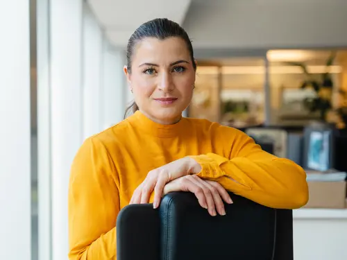 President Elisabet Haugsbø med gul topp i kontorlandskap.  