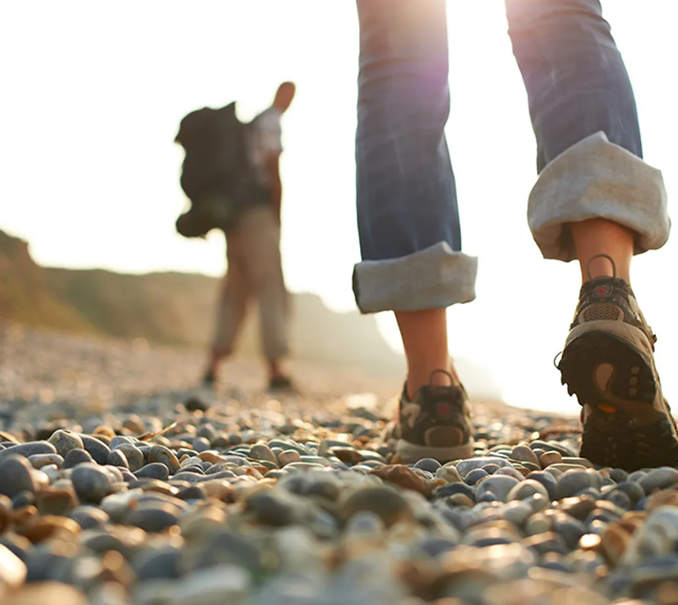 To personer som går tur på steinete strand