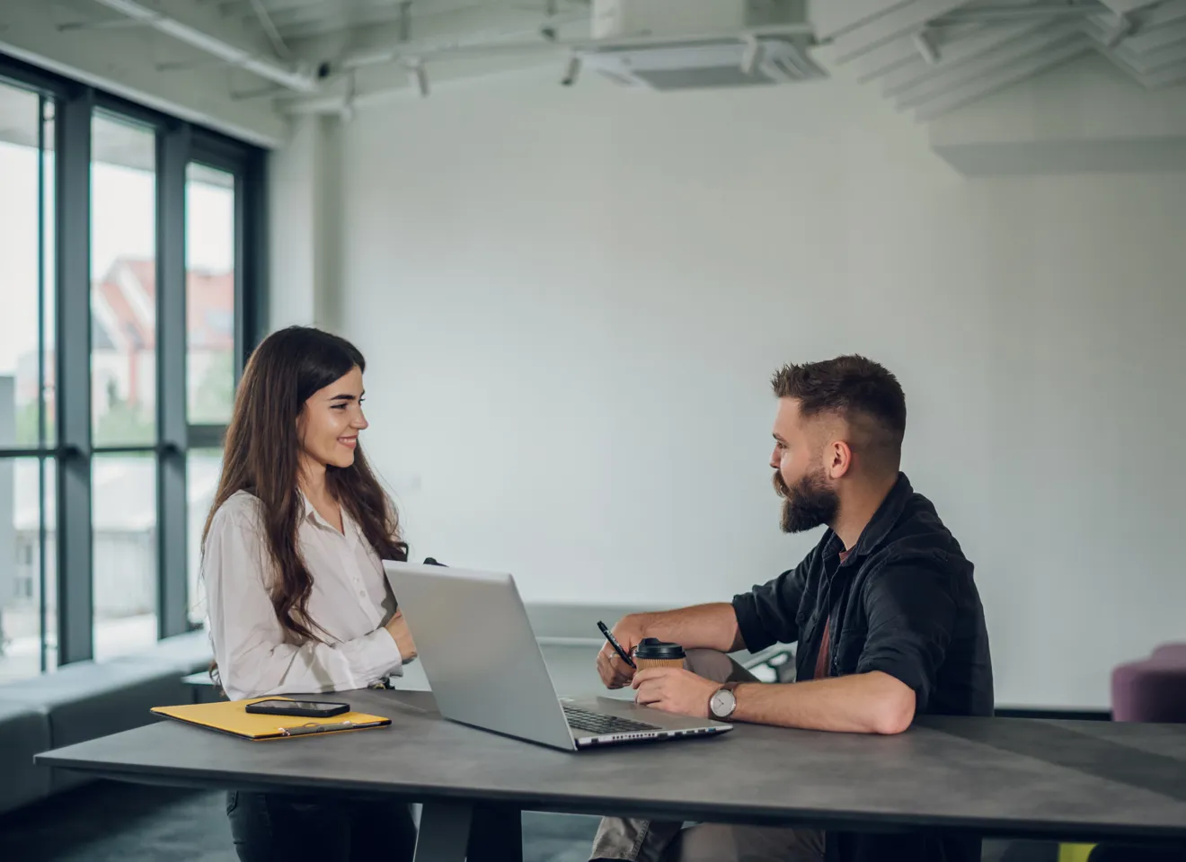 Mann og dame diskuterer foran PC