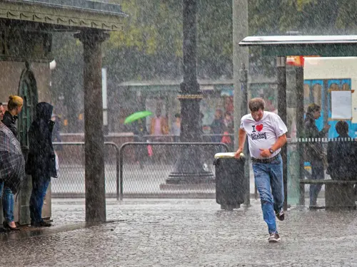 Regnvær i en by med mennesker som søker ly