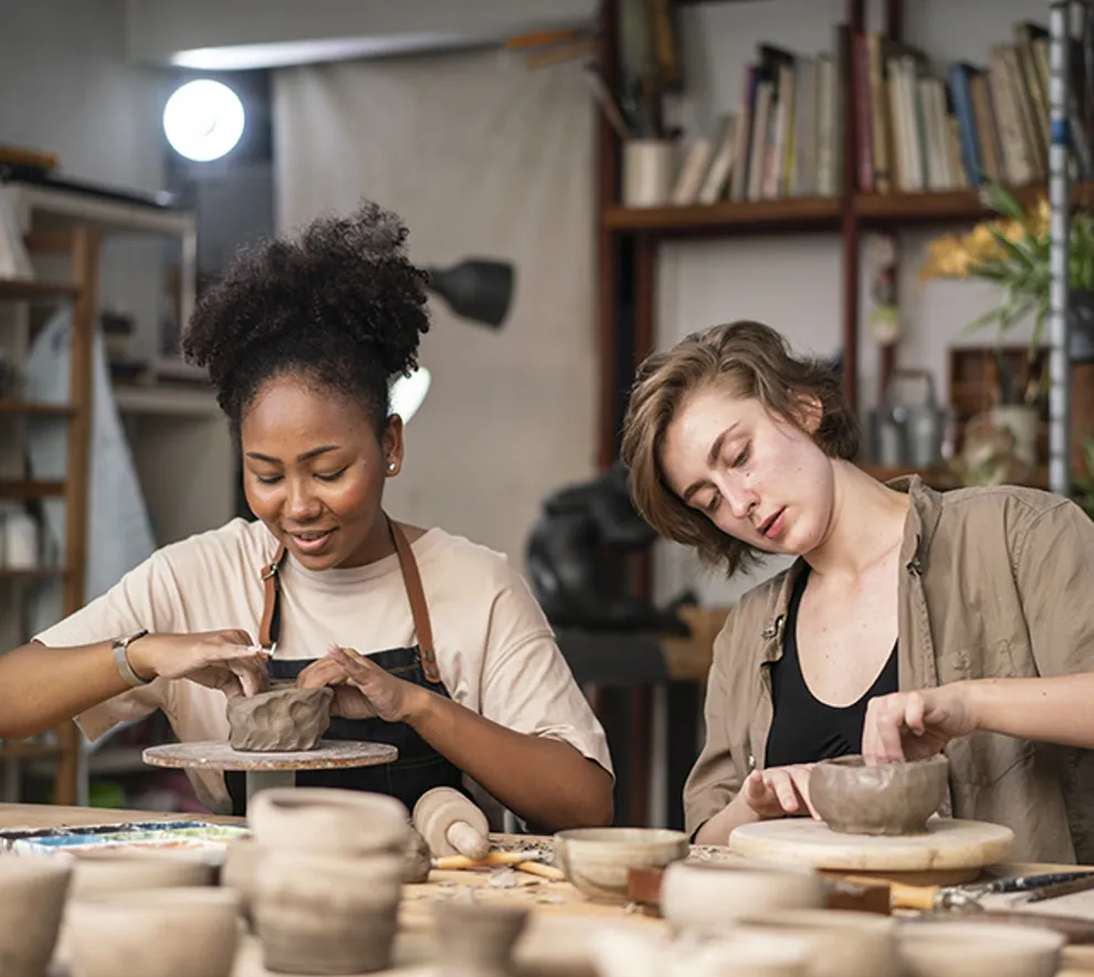 To studenter som lager sin egen gjenstand i leire