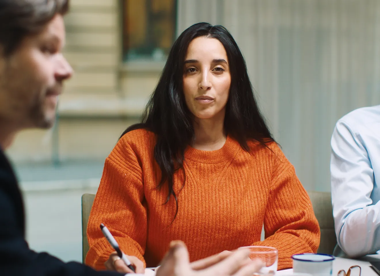 Kvinne rundt et bord ser rett inn i kameraet