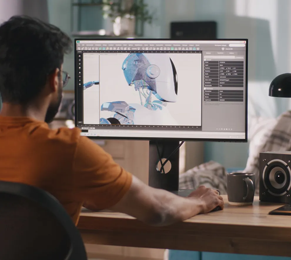 Mann jobber med en 3d-modell på datamaskinen sin, sett bakfra, med en kompleks modell på skjermen.