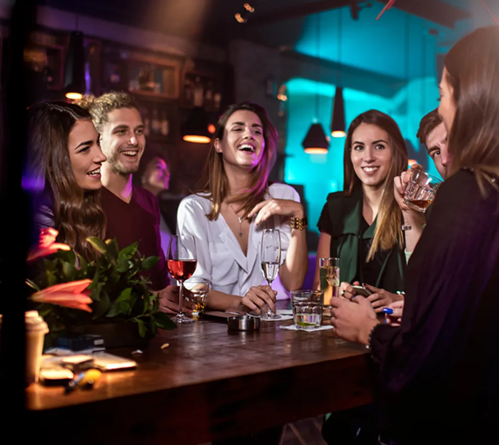 Venner står samlet rundt et bord på en bar og ler.