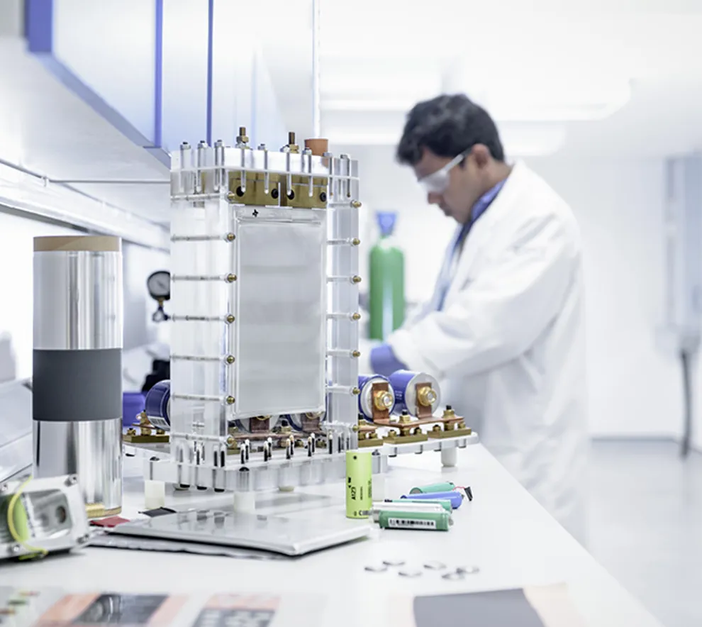 Forsker i laboratorium utvikler avansert batteriteknologi med eksperimentelt brenselcelle-system og litium-ion-komponenter.