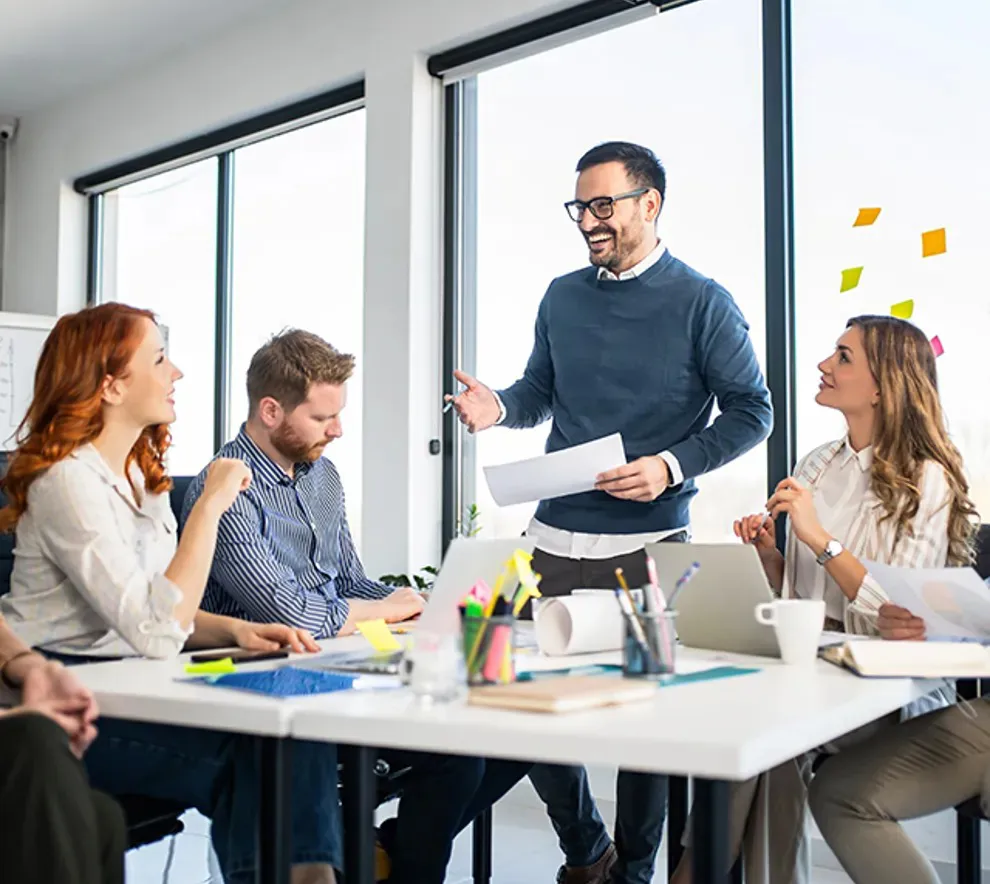 En gruppe kolleger sitter rundt et bord og brainstormer engasjert.
