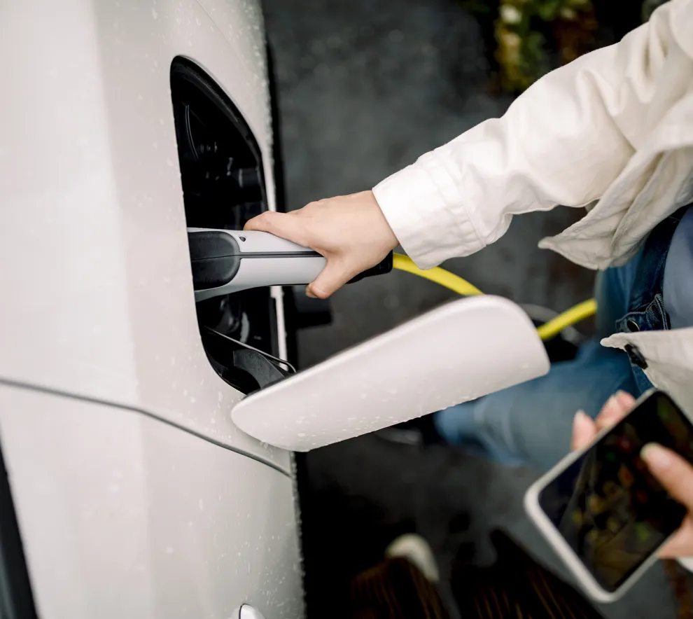Kvinne lader elbilen sin.