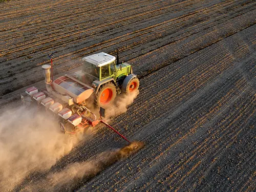 En traktor kjører gjennom en åker og behandler jorden.