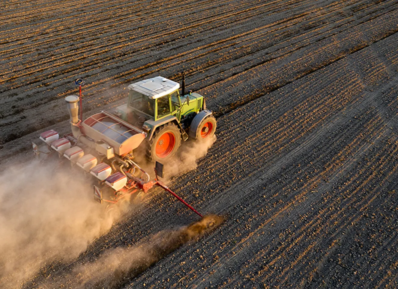 En traktor kjører gjennom en åker og behandler jorden.