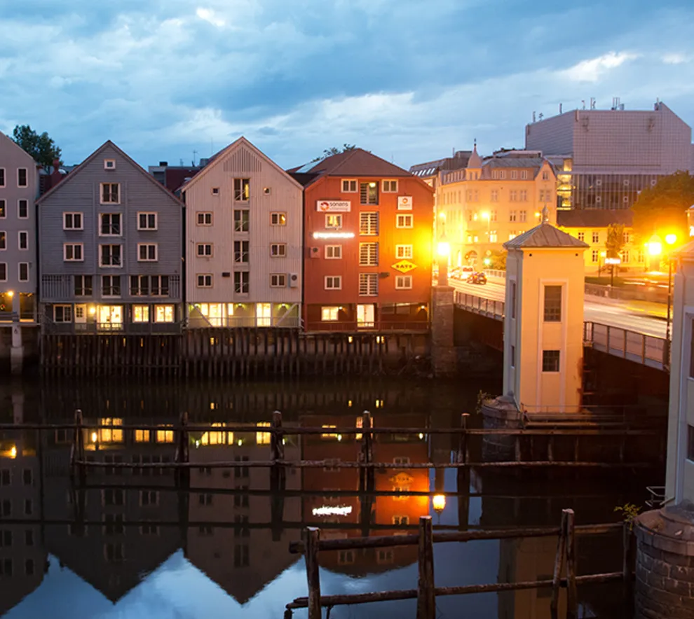 Gamle kjøpmannshus ved vannet i Trondheim i skumringen.